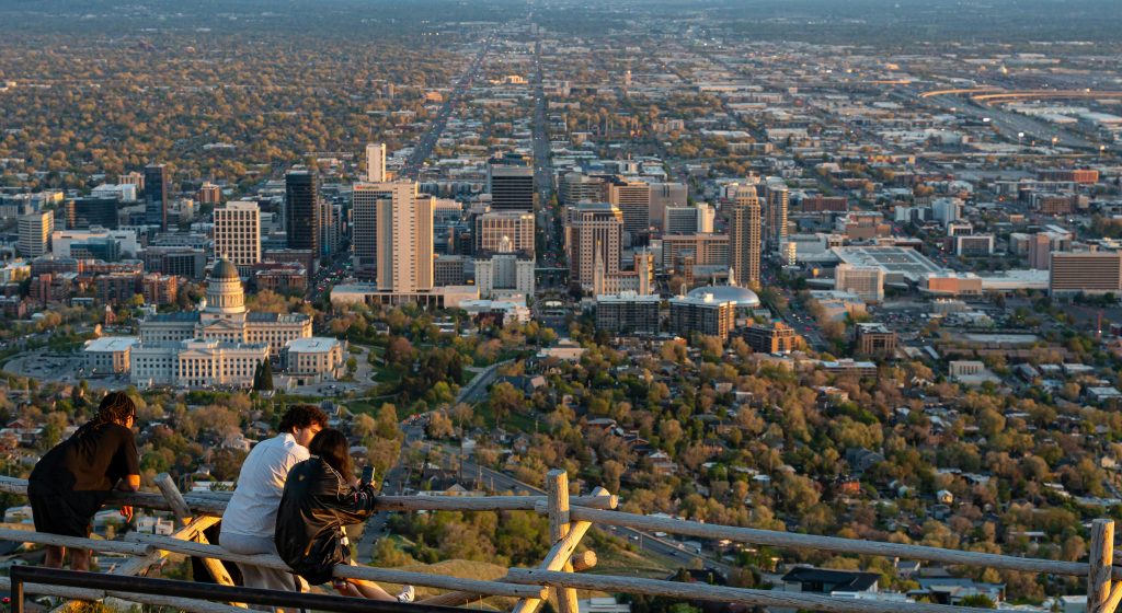 Panoramic view of Salt Lake City skyline with people enjoying the sunset from a hilltop.
