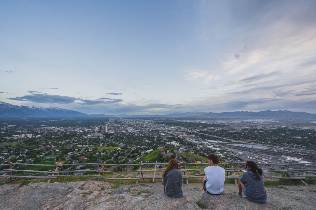 Group of friends sitting on a hill enjoying the panoramic cityscape view.